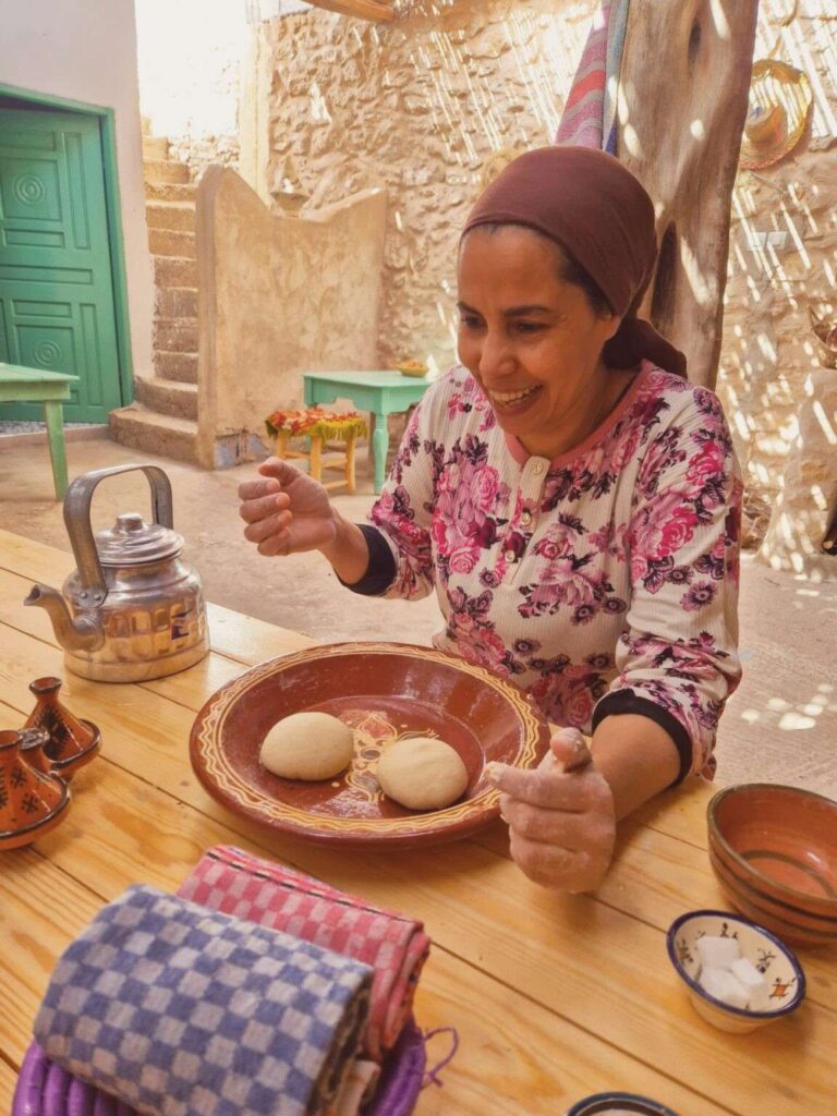 A woman at a table set with traditional Moroccan dishes at the Berber bread workshop