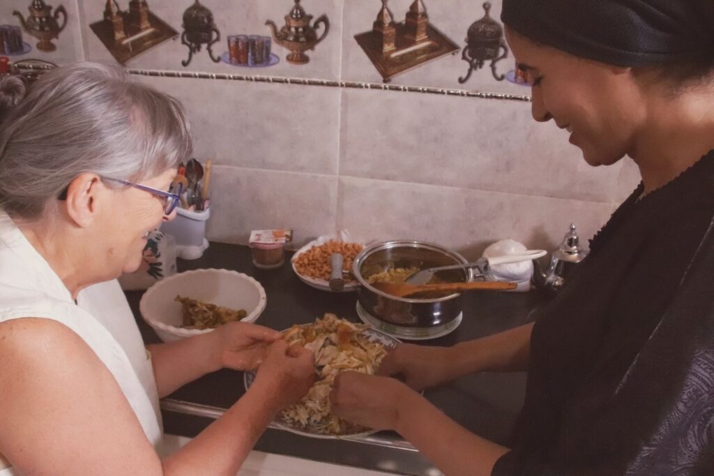 Deux femmes s'affairent à préparer des mets dans une cuisine, participant à un cours de cuisine Marrakech.