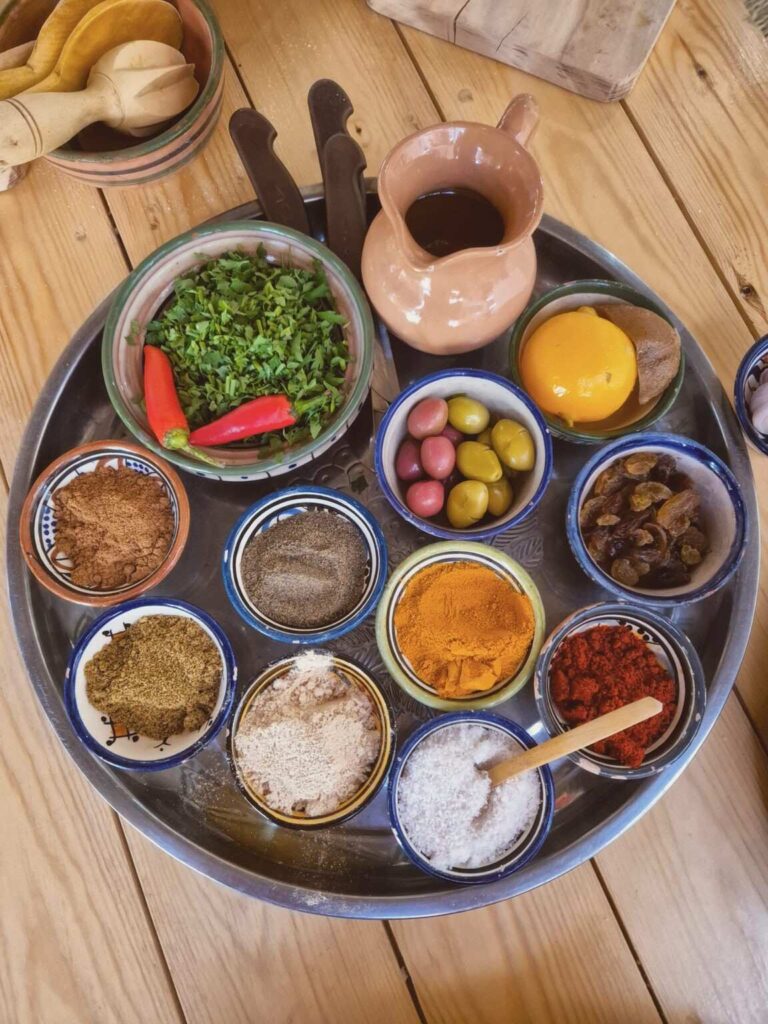 Essaouira cooking class: colorful Moroccan spices and ingredients on a wooden tray