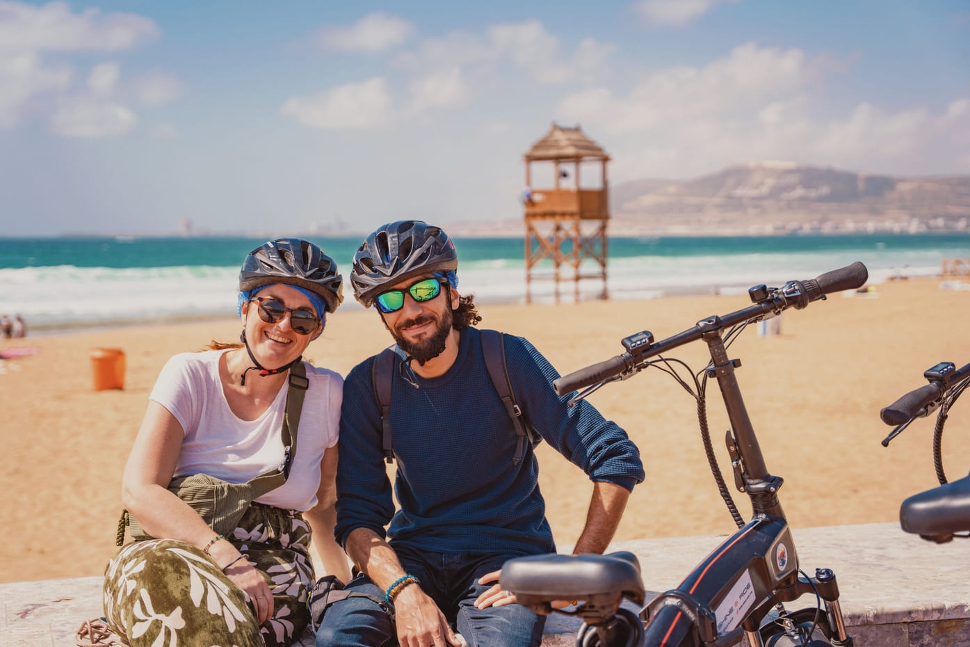 Pause de deux cyclistes casqués sur le front de mer durant la visite à Agadir