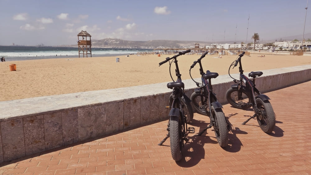 Vélos électriques alignés face à la plage sablonneuse pendant la visite à Agadir