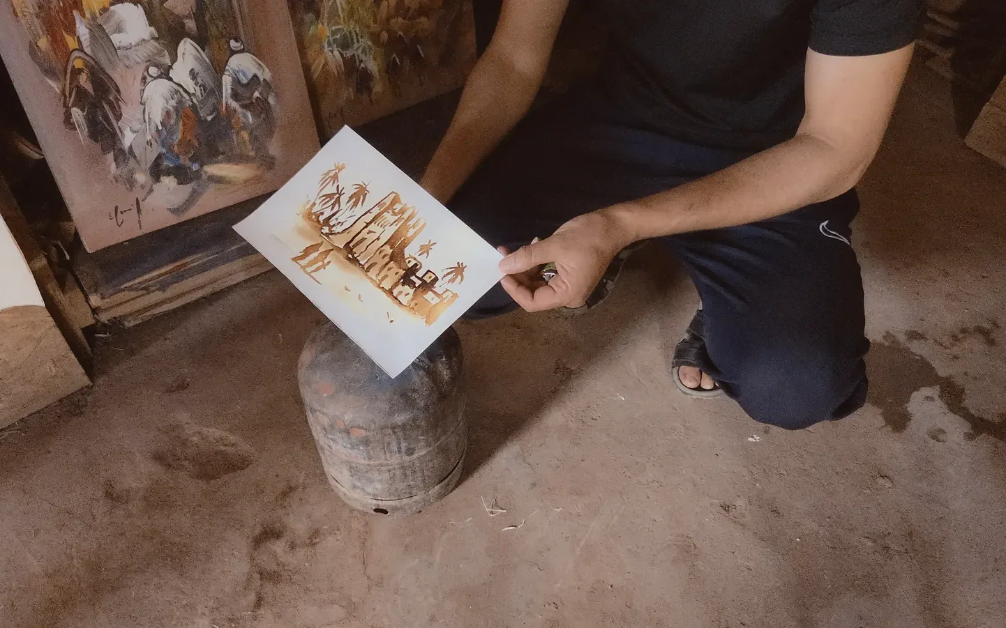 L'artiste passe sa peinture au-dessus de la flamme pour révéler la pyroaquarelle à Aït Ben Haddou