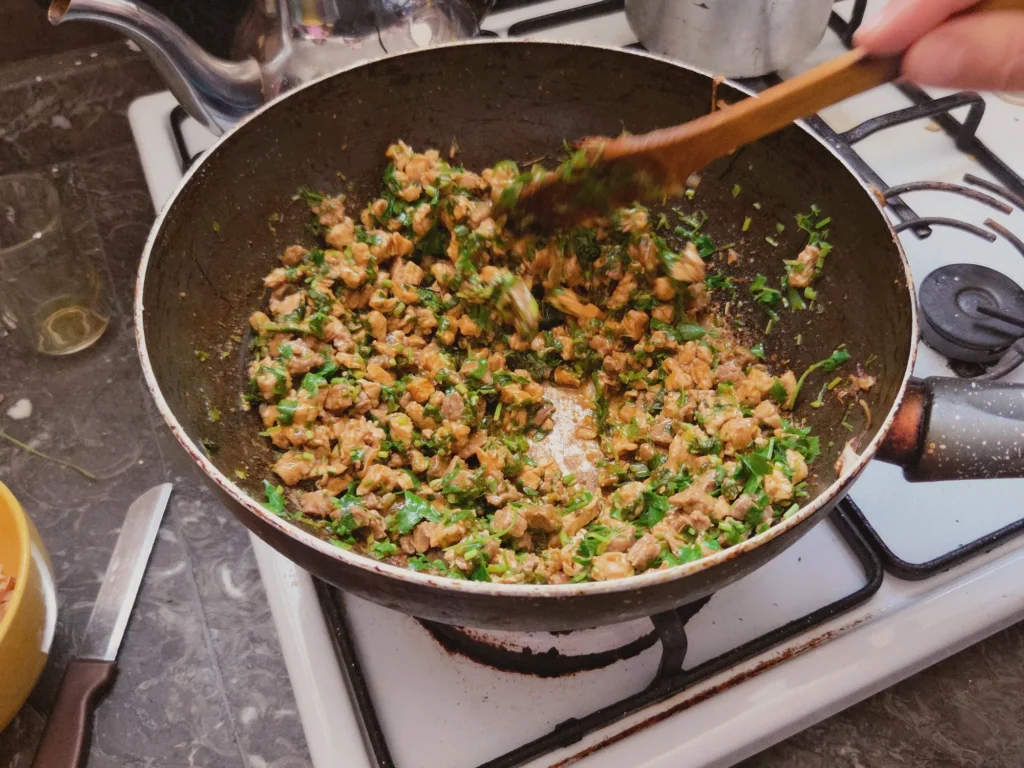 La farce de viande, coriandre et épices revient à la poêle pendant le cours de cuisine à Ouarzazate.