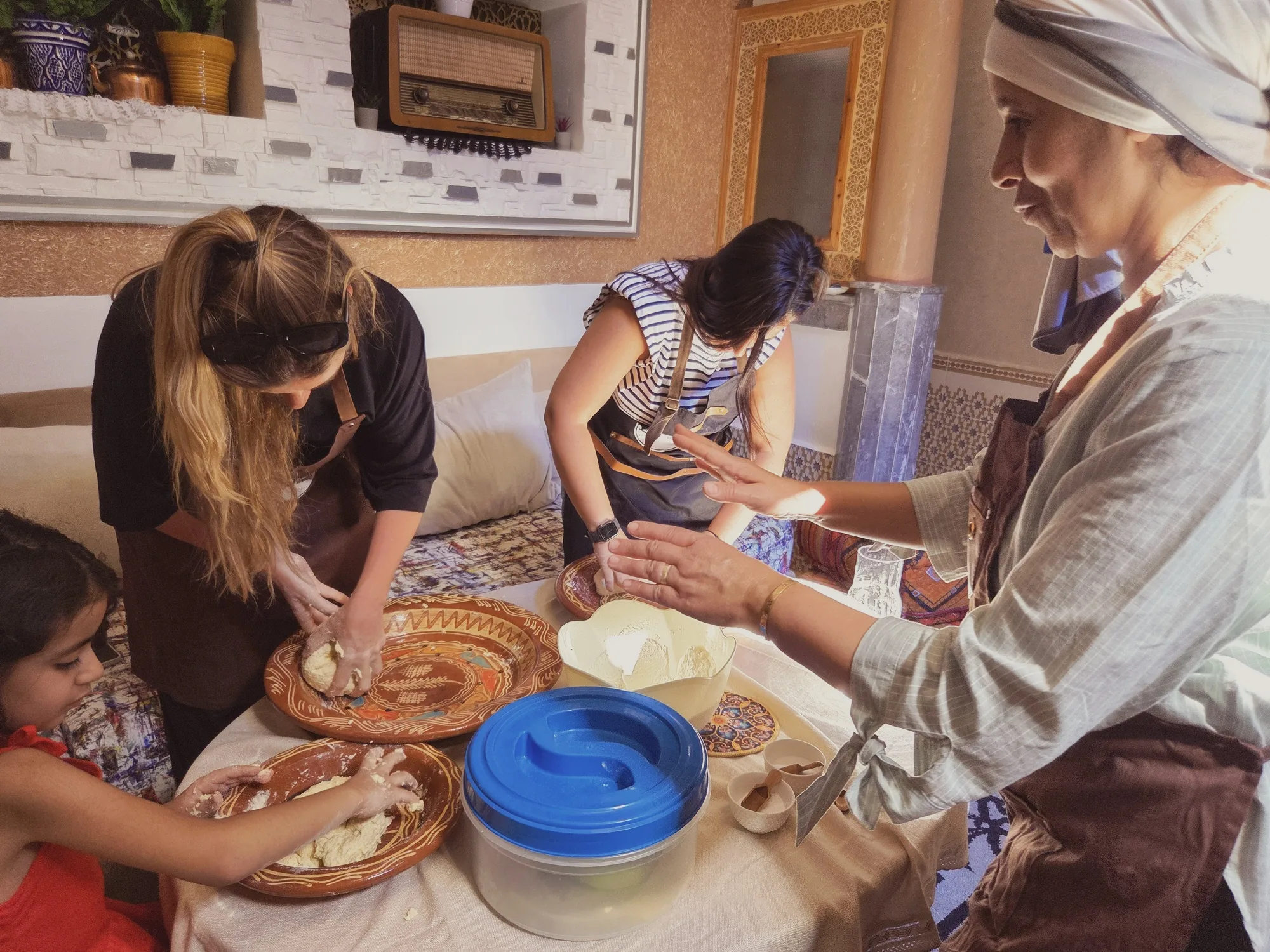 Les invitées et Sofia pétrissent la pâte à la main sous le regard d’Aouatif, pendant le cours msemen à Ouarzazate.