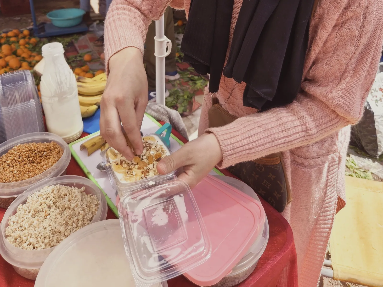 Food tour au souk de Ouarzazate : une marchande remplit une barquette de graines et fruits secs grillés à déguster