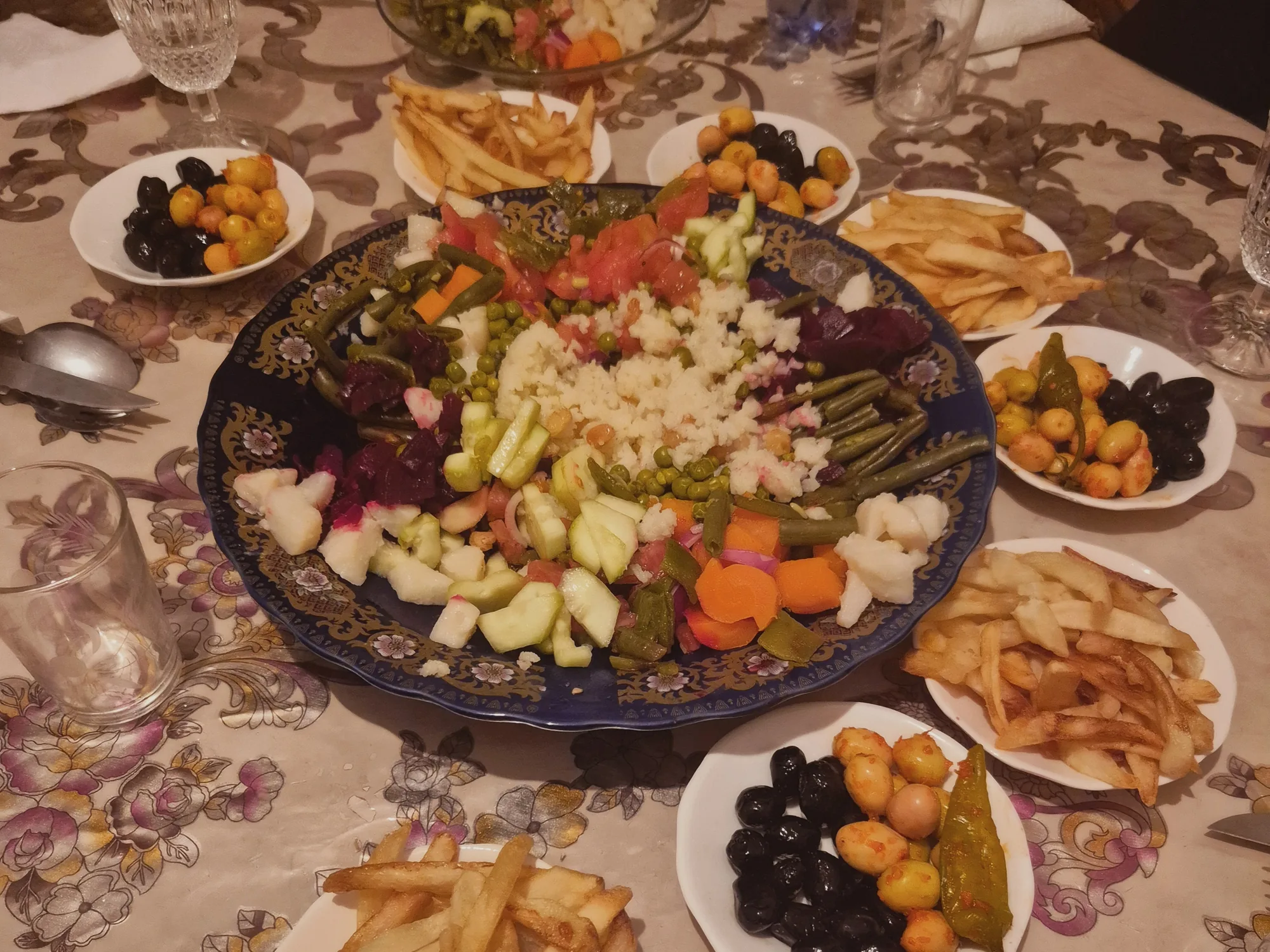 Grande salade marocaine faite maison entourée d'olives et de frites, servie au repas chez l'habitant à Ouarzazate.